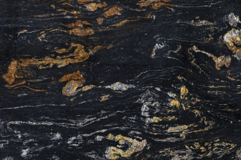 Textura de granito exótico Black Ember con fondo negro intenso y vetas doradas irregulares, utilizada en cubiertas y revestimientos premium