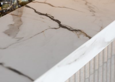 Detalle de canto y terminaciones de ultracompacto Calacatta Luxury en barra de restaurante Margó Chicureo