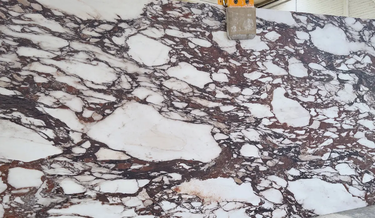 Detalle de placa de mármol Calacatta Viola con vetas burdeos marcadas sobre fondo blanco, utilizado en diseño interior premium.