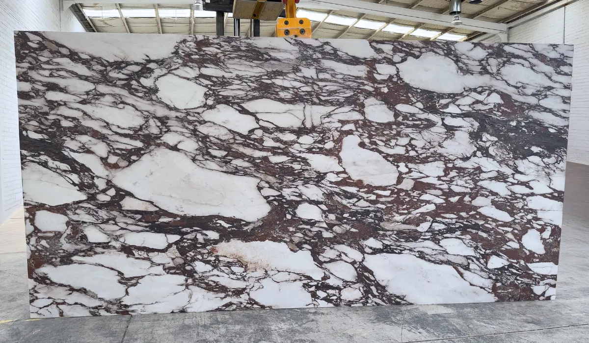 Placa completa de mármol Calacatta Viola en bodega, piedra natural blanca con vetas vino de gran contraste.