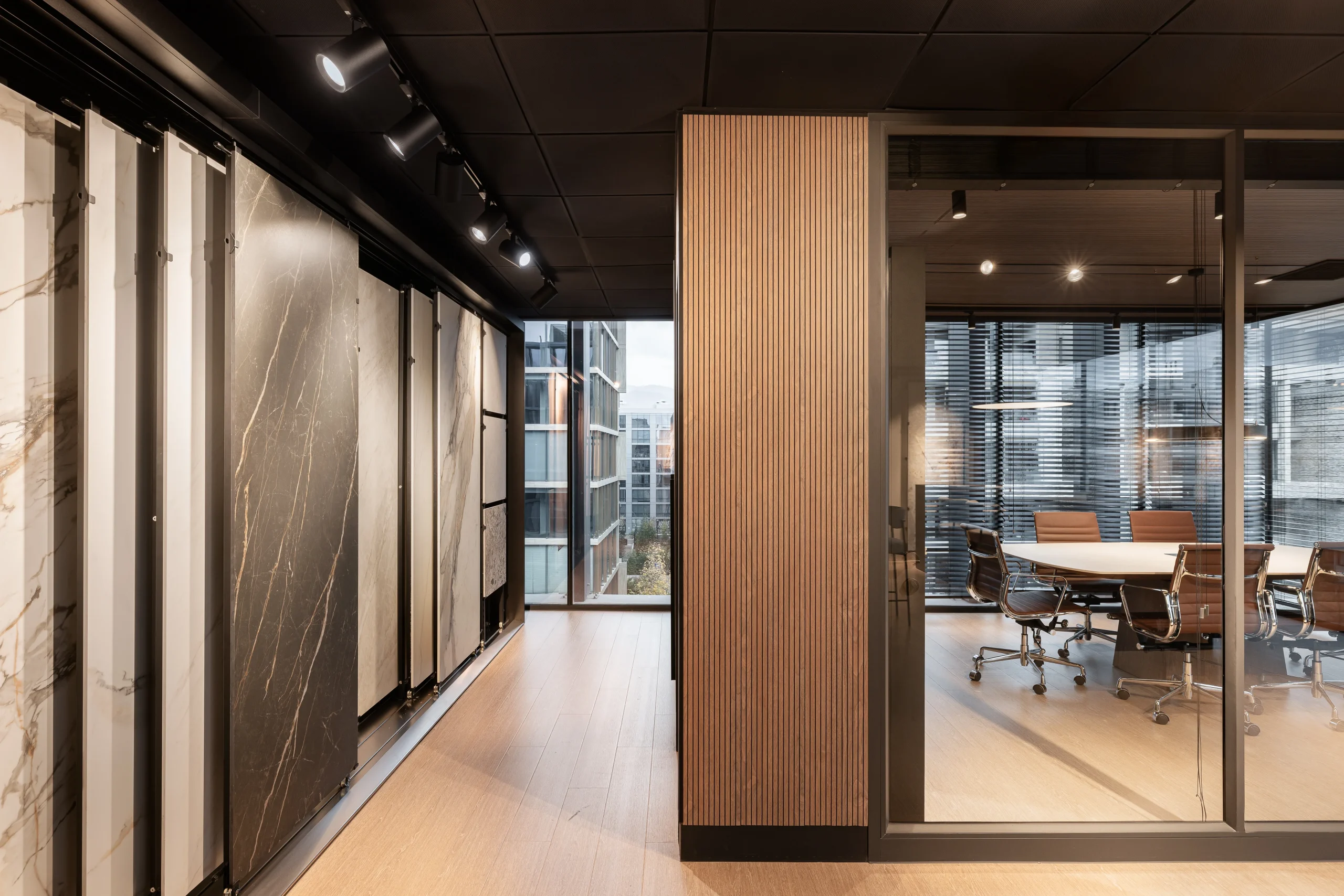 Corredor del showroom Casamura con paneles de mármol y vista a sala de reuniones