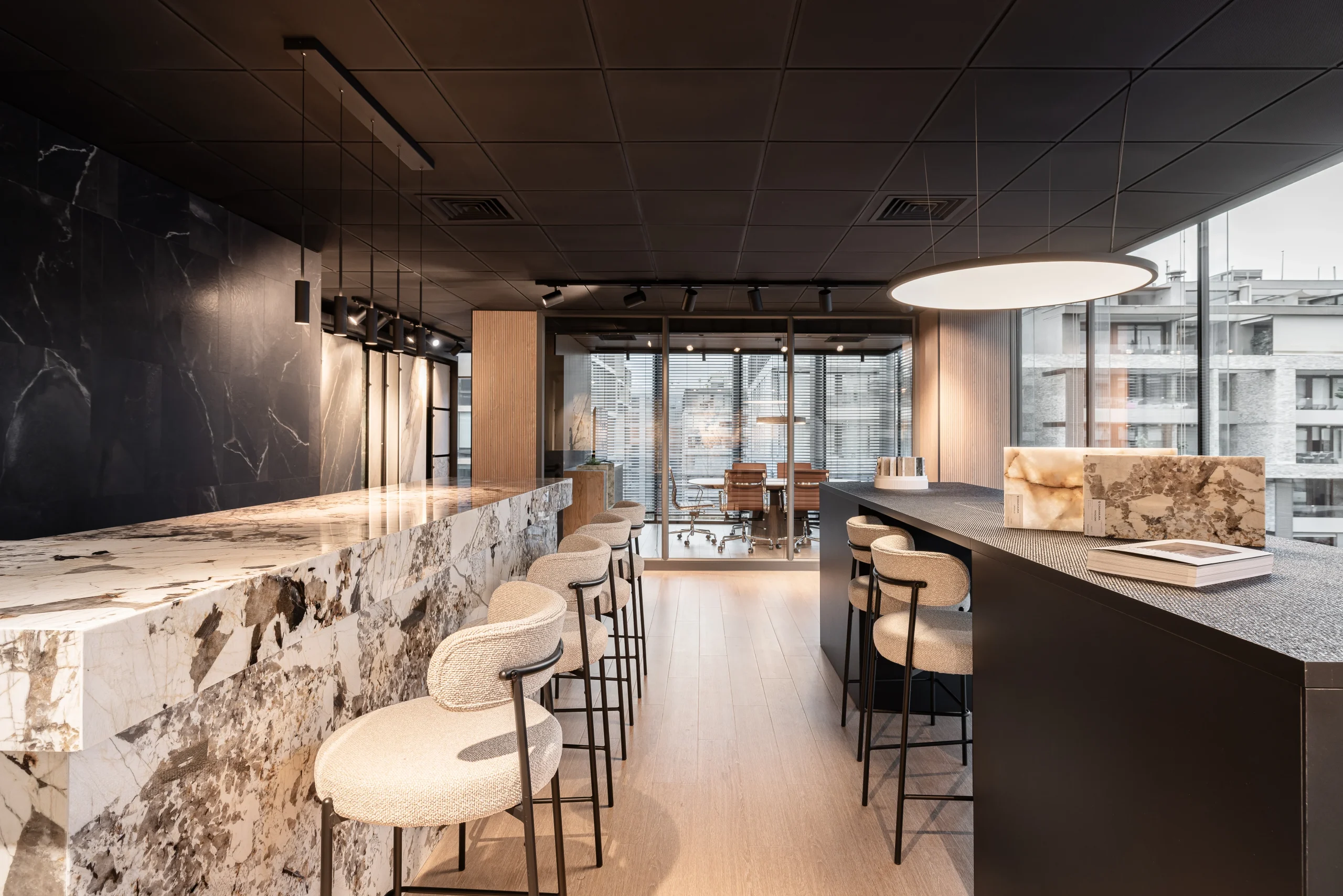 Showroom Casamura con mesones de mármol natural y taburetes en isla de cocina
