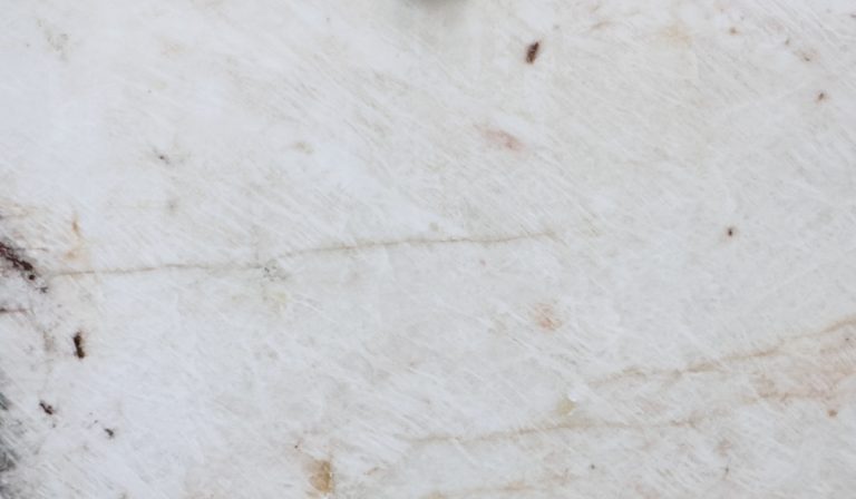 Detalle de superficie de cuarcita Cristallo Exótica blanca con vetas beige cálidas e inclusiones oscuras.